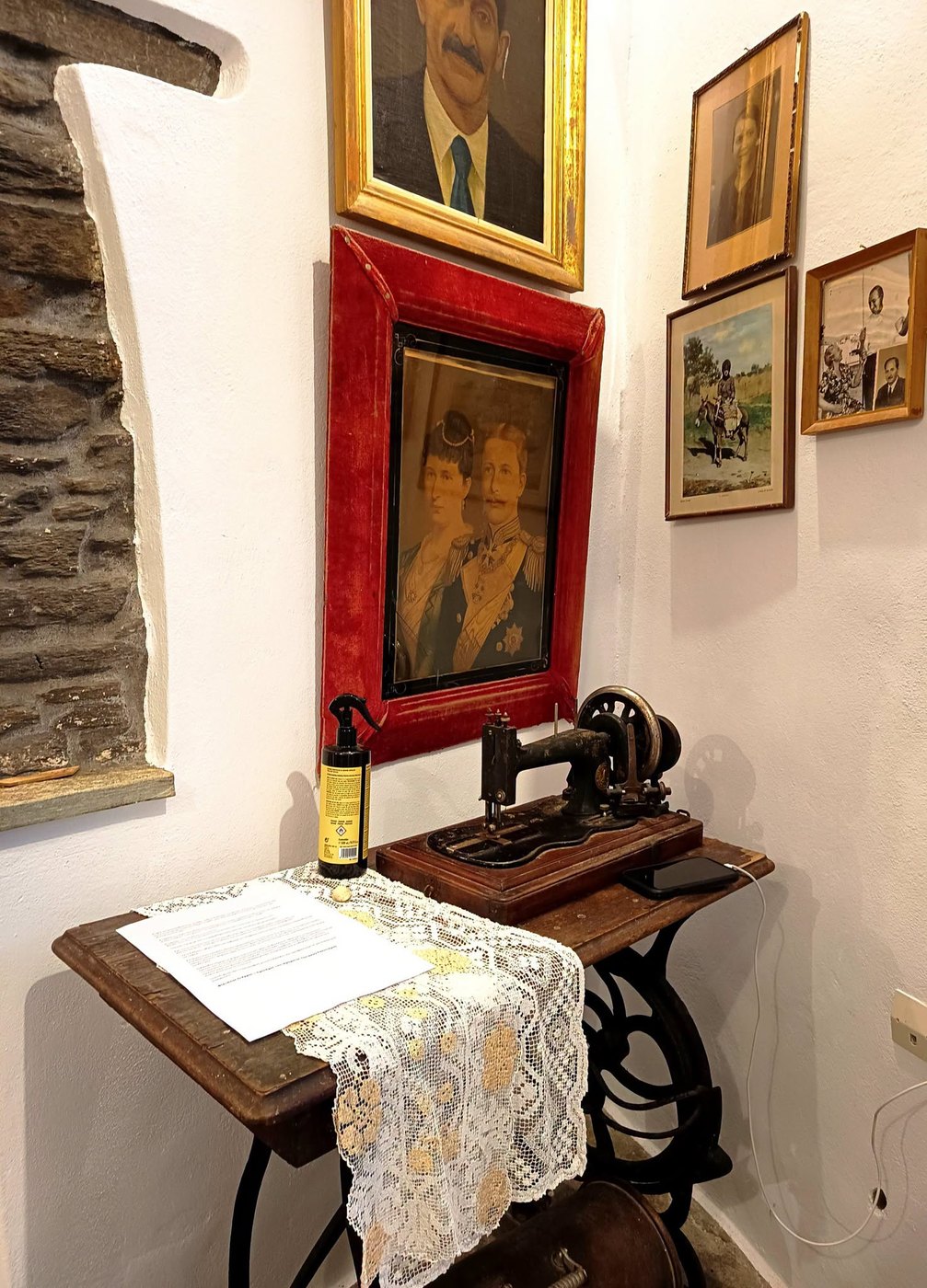 Παλιά ποδοκίνητη ραπτομηχανή κάτω από κορνιζαρισμένες οικογενειακές φωτογραφίες