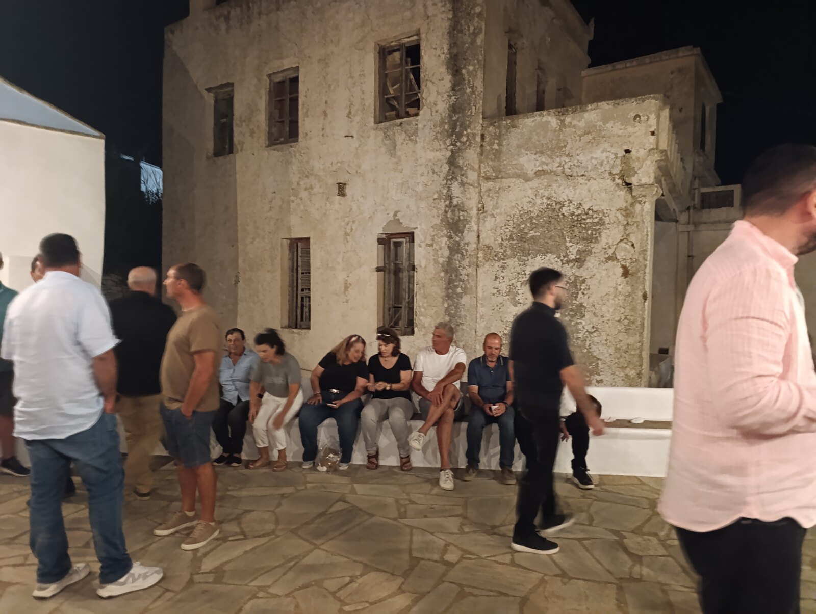 Κόσμος στην αυλή, μπροστά από το πέτρινο κτίριο
