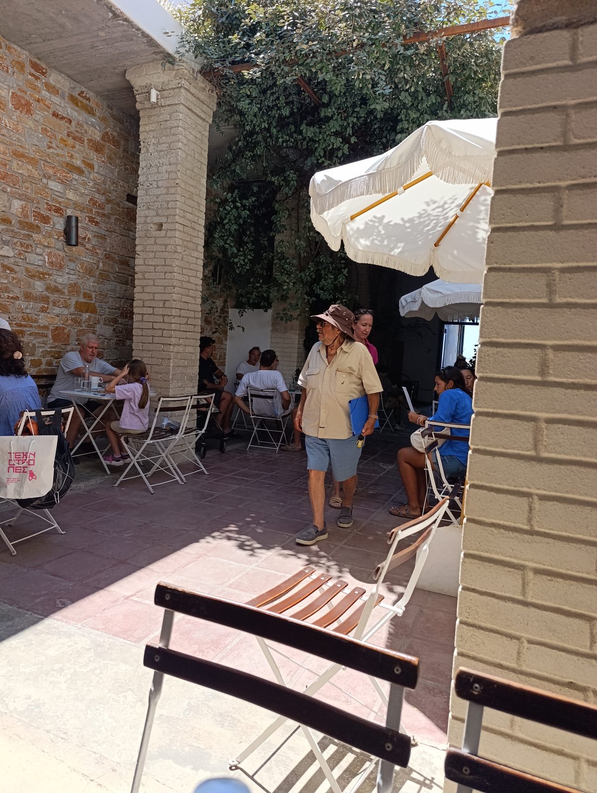 Αυλή καφέ στη Χώρα της Τήνου με τραπέζια στη σκιά