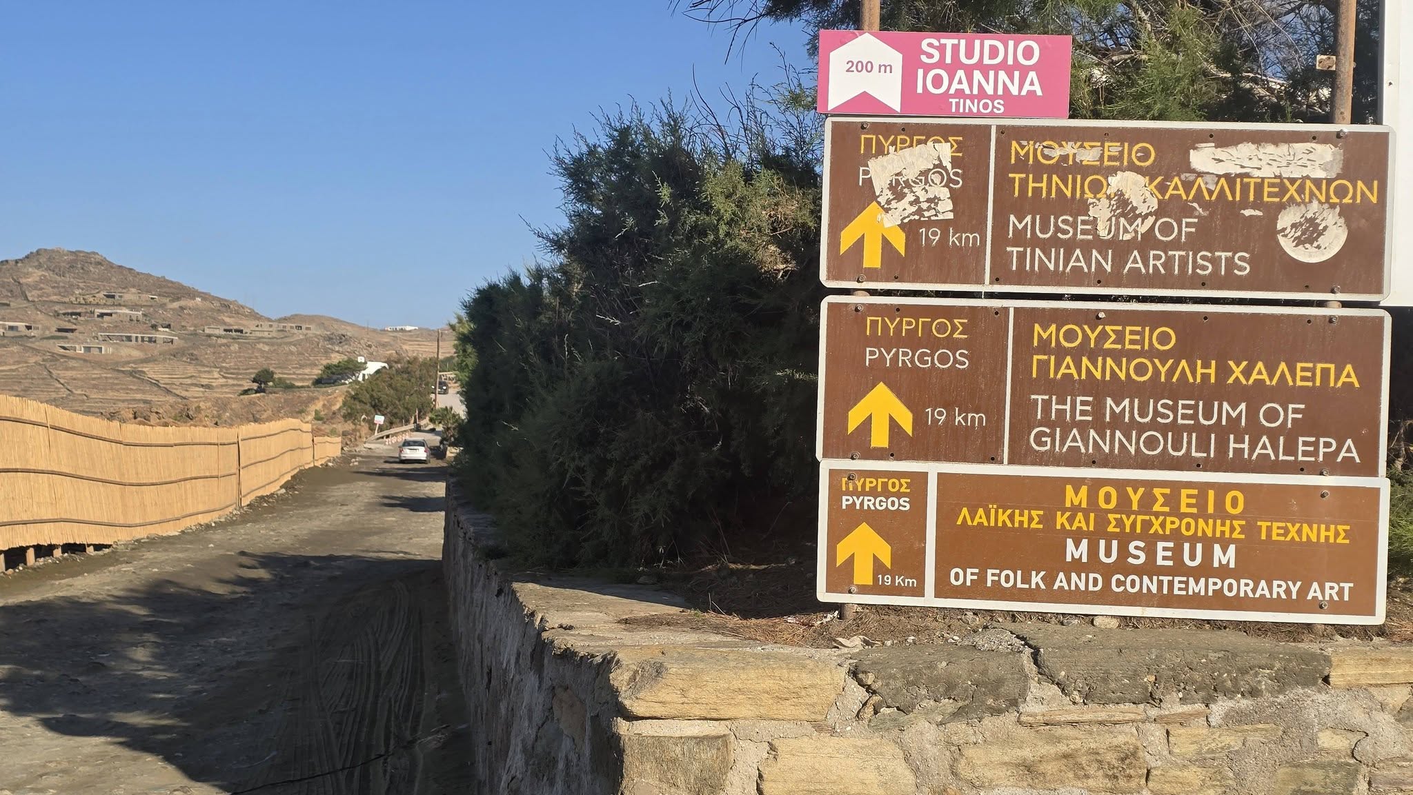 Τουριστικές πινακίδες για Πύργο και μουσεία πάνω από χωματόδρομο στα Κιόνια