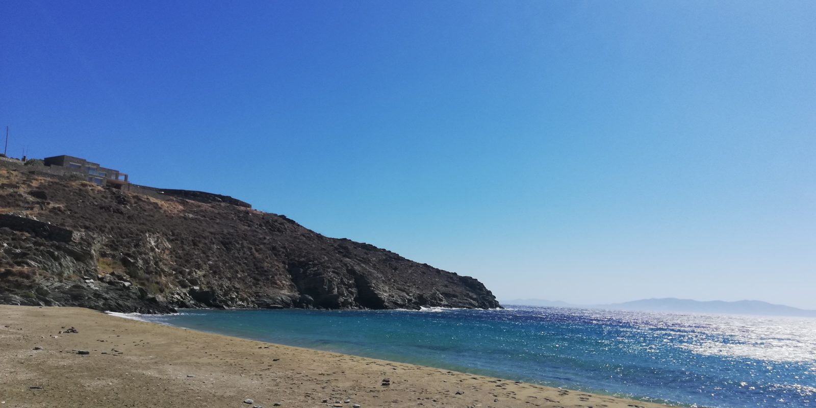 Η παραλία της Καντάνης με τον βραχώδη λόφο και ένα κτίσμα στην κορυφή