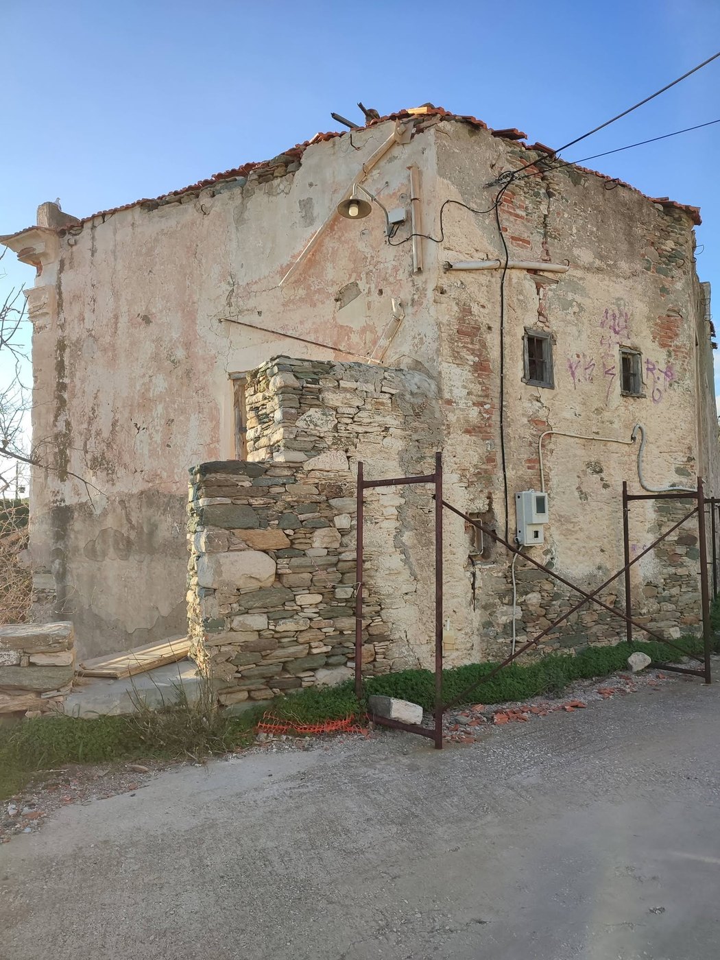 Πρόχειρη μεταλλική περίφραξη στην πλευρά του σπιτιού που ακουμπά στον δρόμο