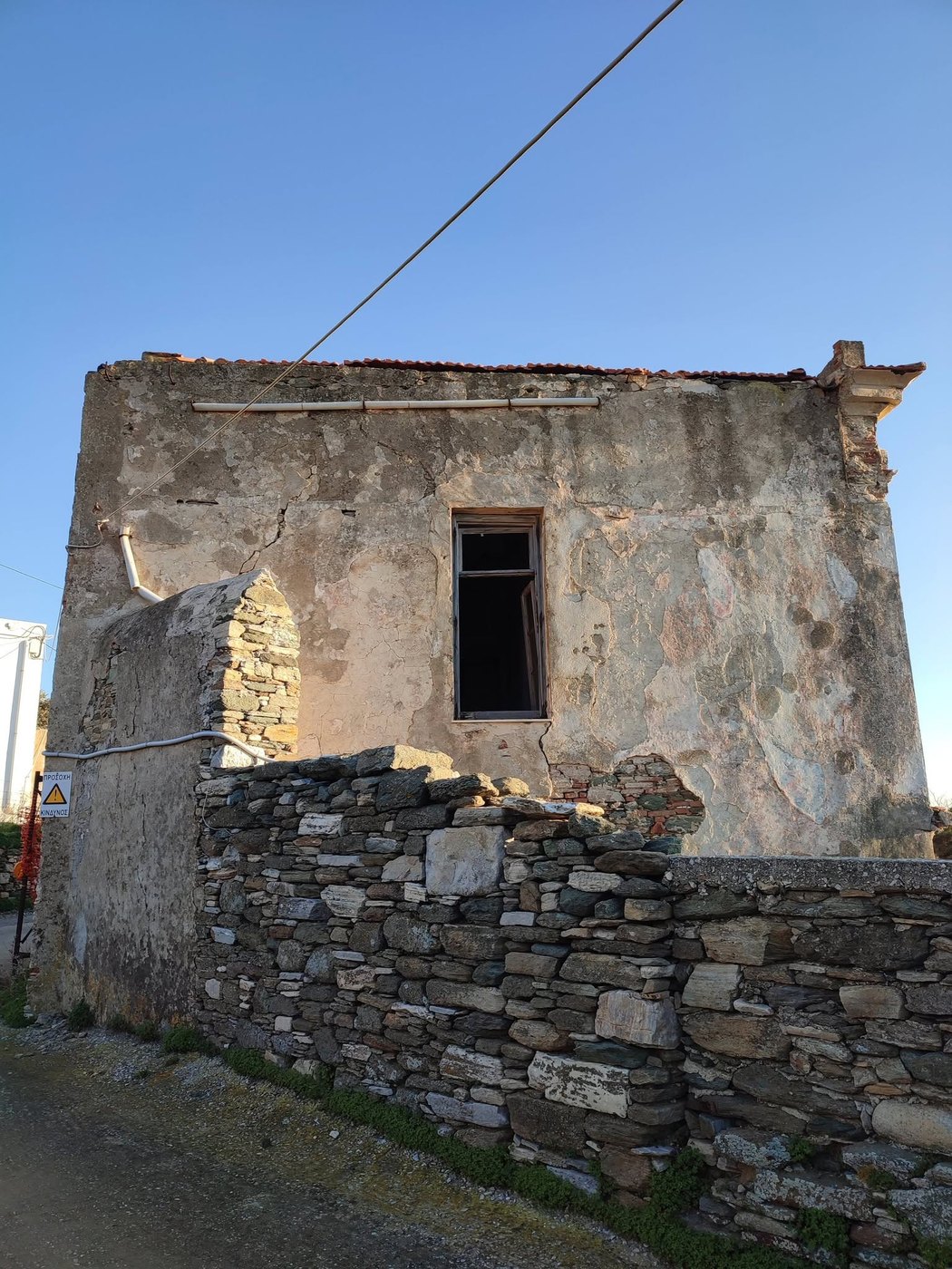 Η πλευρά του σπιτιού προς τον δρόμο, με τον σοβά να έχει φύγει και την πέτρα ακάλυπτη