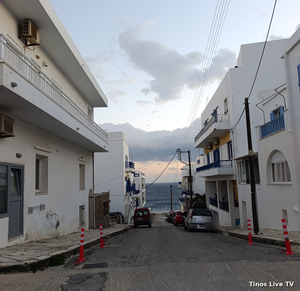 Η κατηφόρα της Οδού Λαζάρου Λαμέρα προς τη θάλασσα με τα κολωνάκια στις δύο γωνίες και σταθμευμένα αυτοκίνητα πιο κάτω, εκτός γωνίας