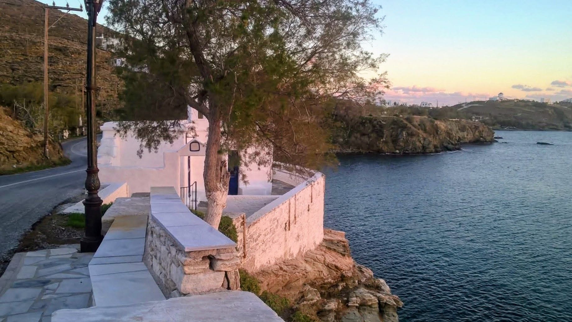 Πανοραμική του Αγίου Μάρκου Τήνου από τον δρόμο, με το εκκλησάκι, τη θάλασσα και το απέναντι ακρωτήρι