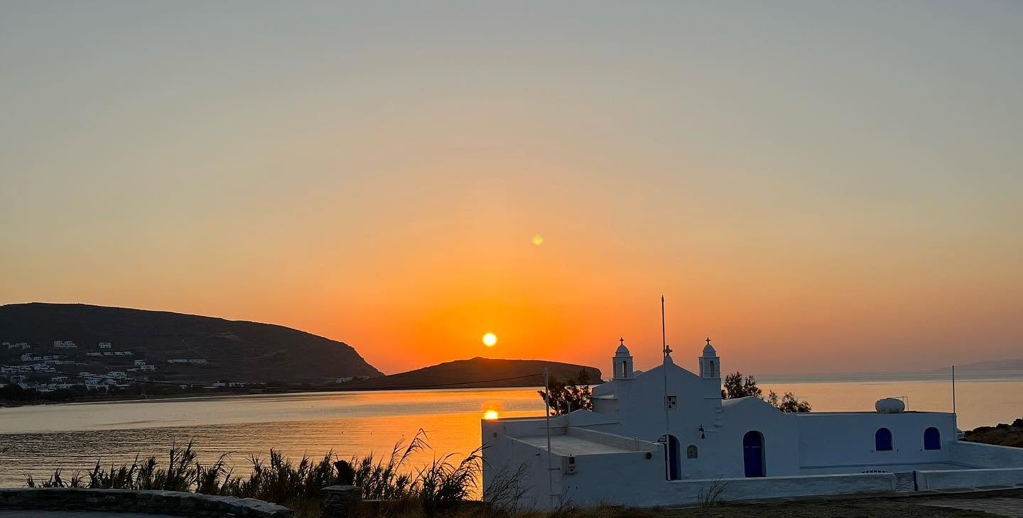 Το εκκλησάκι του Αγίου Σώστη στην Τήνο την ώρα της ανατολής του ήλιου, με τον όρμο πίσω του