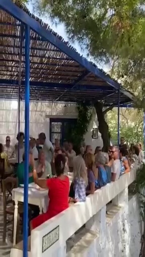 Μακριά τραπέζια κάτω από μπλε πέργκολα με καλαμωτή στον Αρνάδο Τήνου