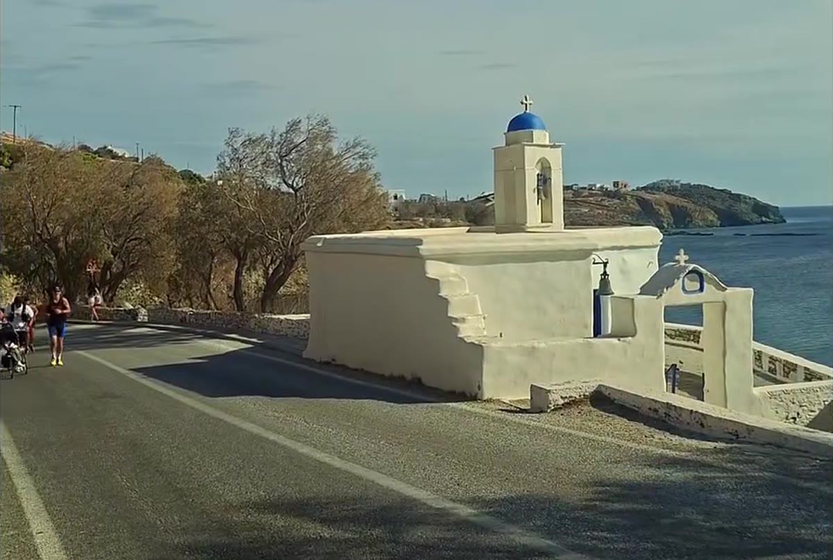 Δρομείς με καρότσι στον παραλιακό δρόμο της Τήνου, δίπλα σε ξωκλήσι