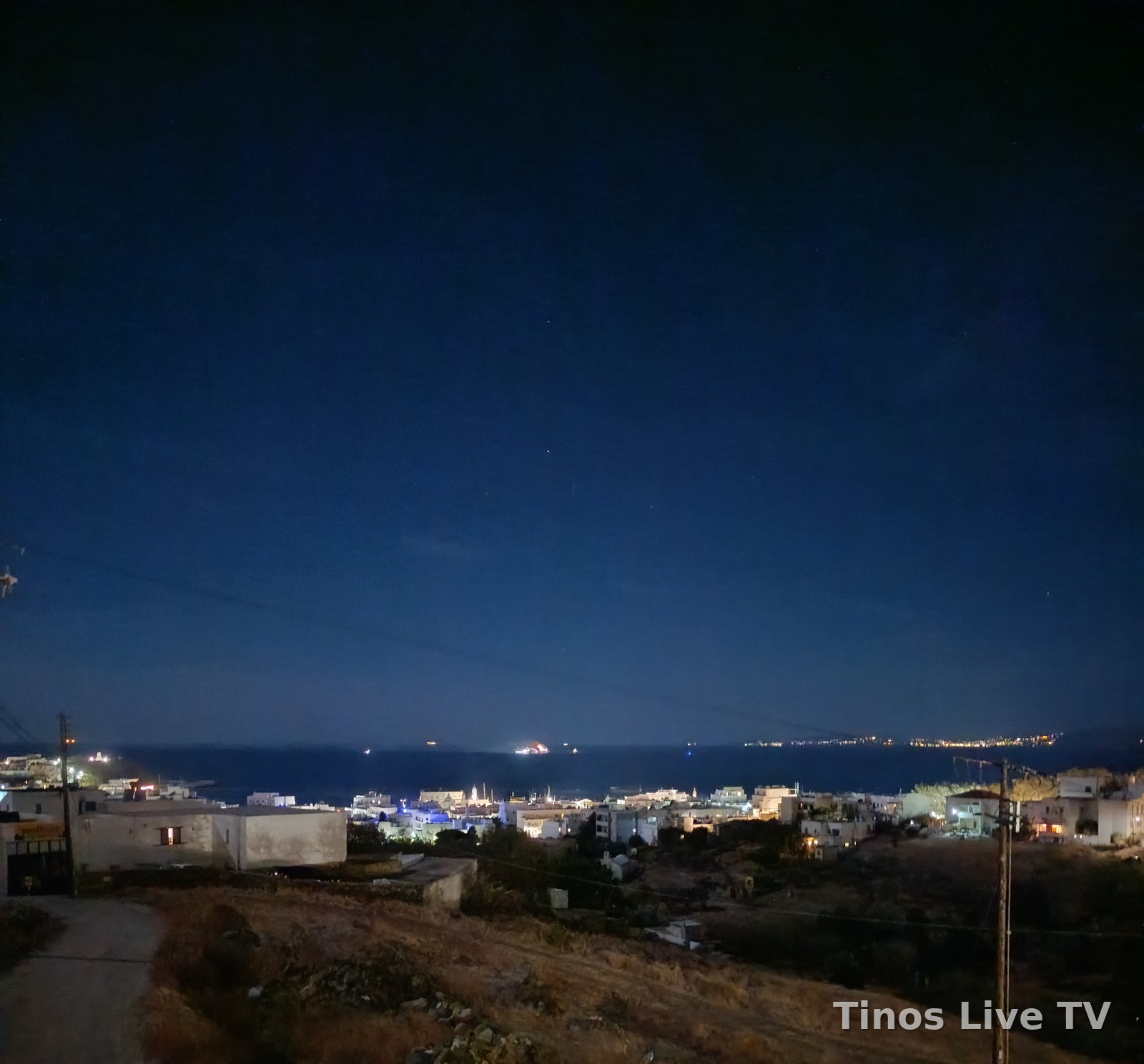 Η θέα από τα υψώματα πάνω από τη Χώρα της Τήνου, με το φλεγόμενο πλοίο στον ορίζοντα, 22:42