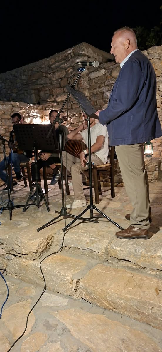 Ομιλητής στο μικρόφωνο με μουσικούς, το βράδυ στον Αρχαίο Πύργο της Αγίας Τριάδας στην Αμοργό