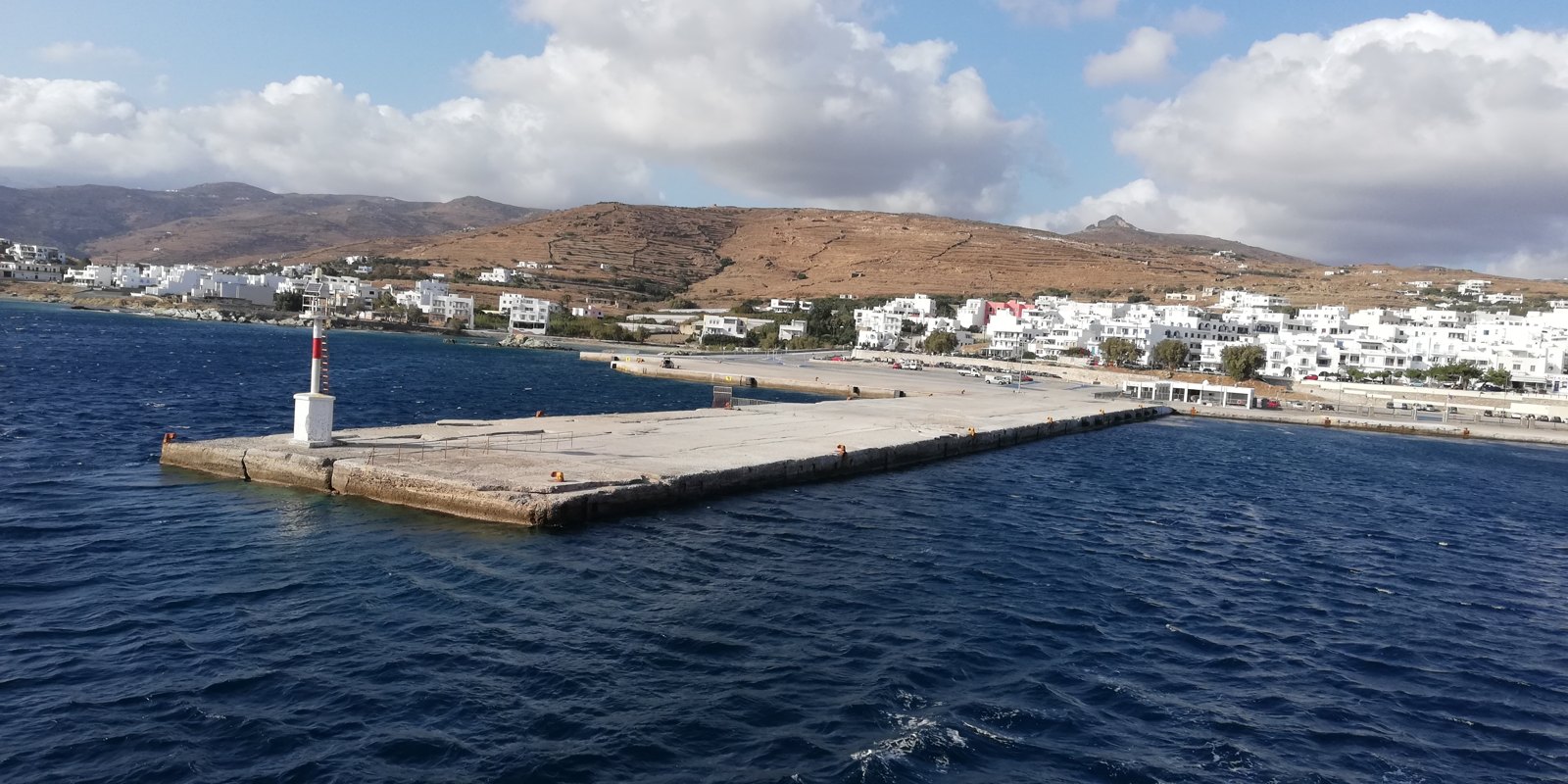 Ο προβλήτας του νέου λιμανιού της Τήνου με τον φανό, από τη θάλασσα, με τη Χώρα στο βάθος