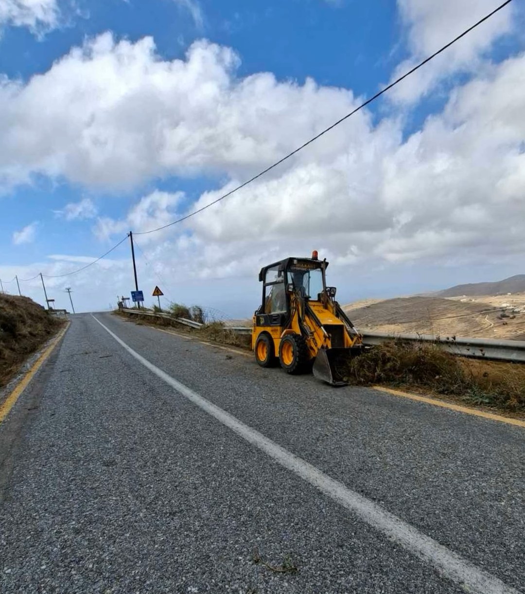 Μηχάνημα έργων στην άκρη ασφαλτοστρωμένου δρόμου της Τήνου, δίπλα στο προστατευτικό κιγκλίδωμα