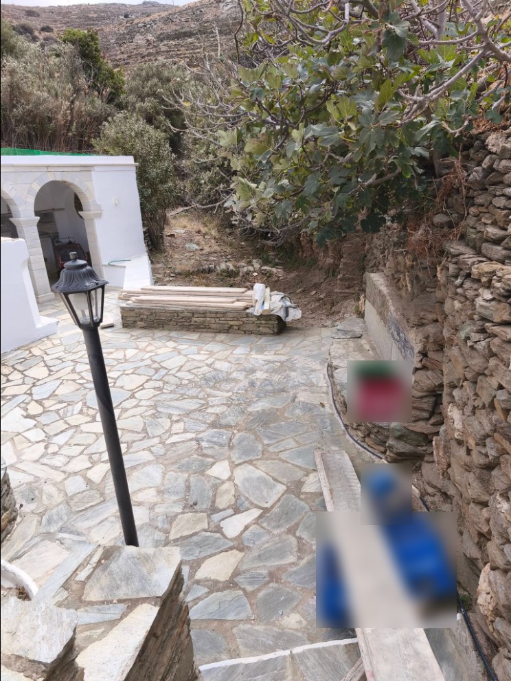 Σανίδες και τελάρα στην πλακόστρωτη αυλή του Πηγαδιού στα Πλατιά της Τήνου
