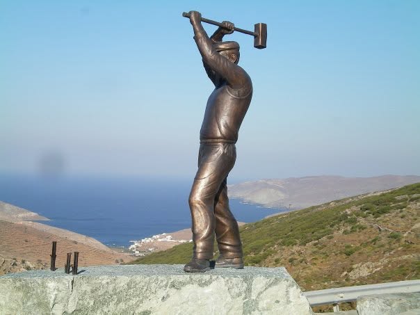 Ο μπρούτζινος λατόμος με τη βαριά στην είσοδο του Μαρλά, με τη θάλασσα στο βάθος
