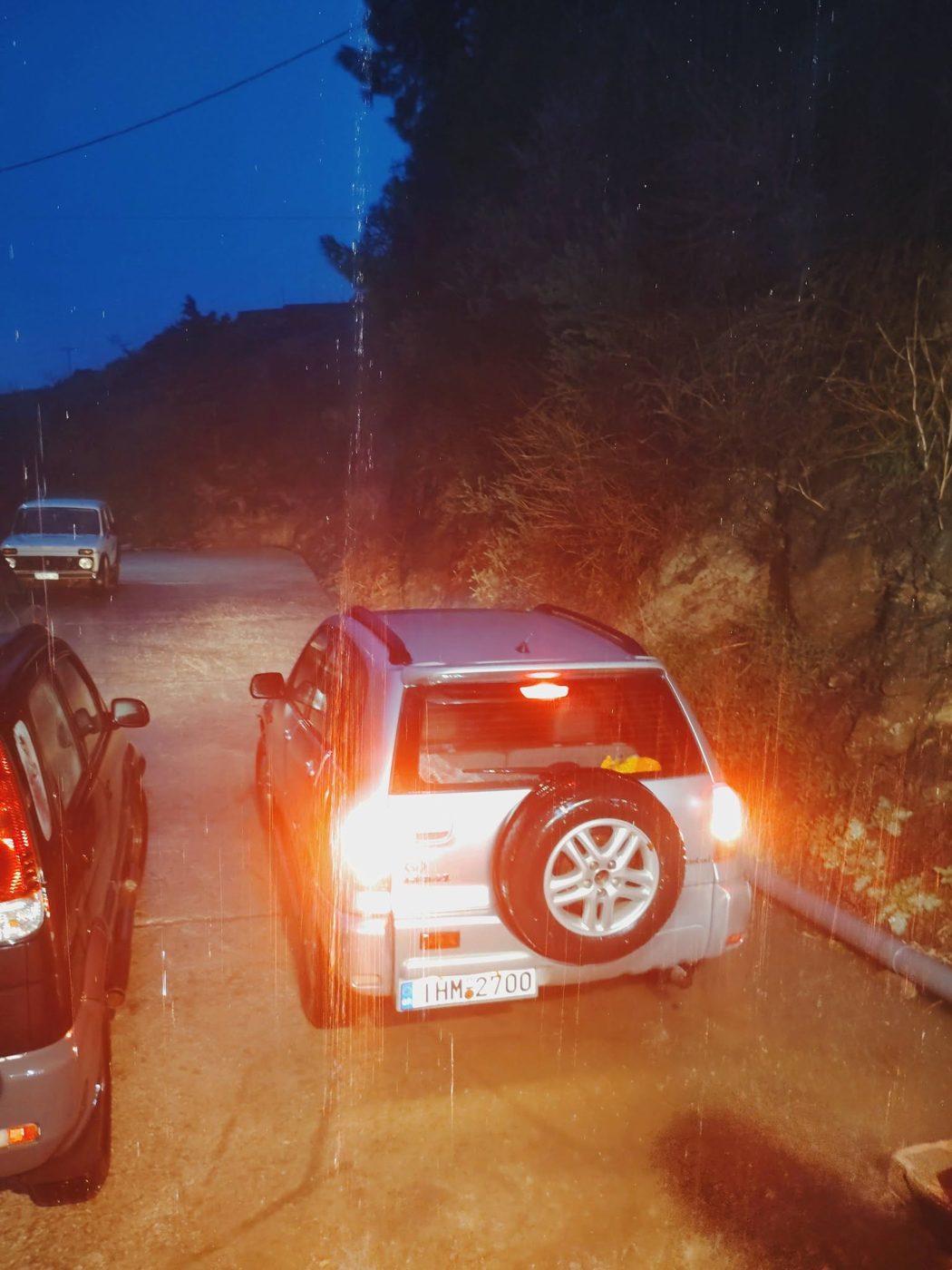 Αυτοκίνητο με αναμμένα φώτα μέσα στη βροχή έξω από το ελαιοτριβείο τη νύχτα