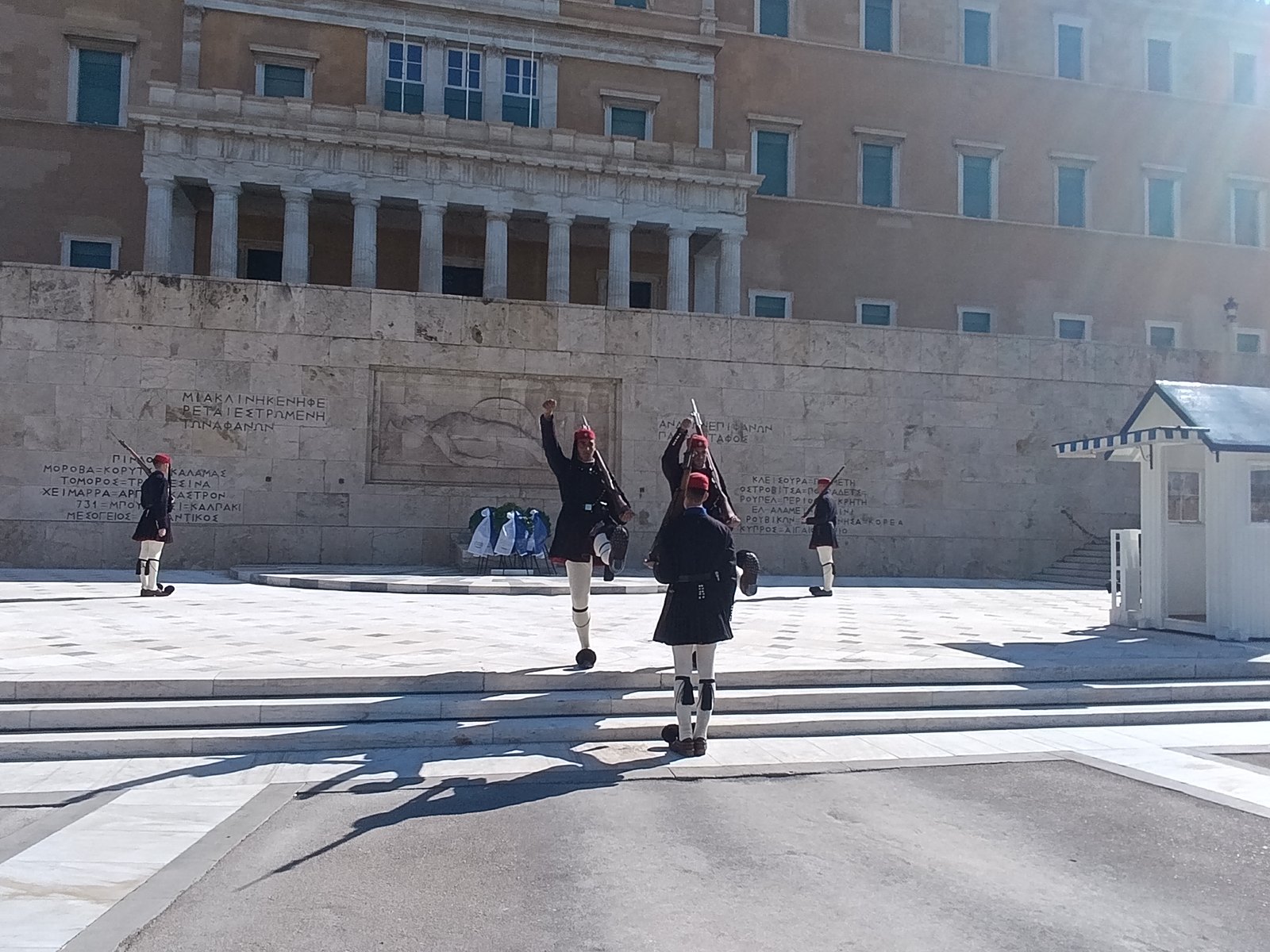 Εύζωνες σε αλλαγή φρουράς μπροστά στο Μνημείο του Άγνωστου Στρατιώτη και τη Βουλή, με στεφάνια στη βάση του μνημείου