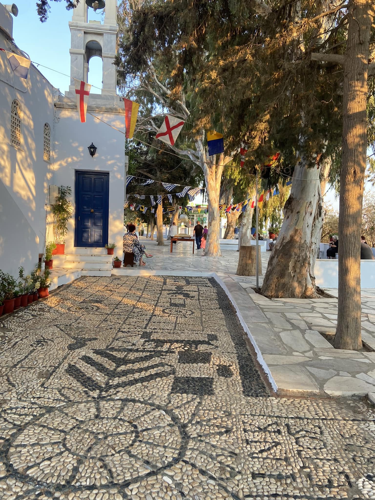 Ο Ναός της Αγίας Παρασκευής στην πόλη της Τήνου, με το βοτσαλωτό και τα σημαιάκια στον αυλόγυρο