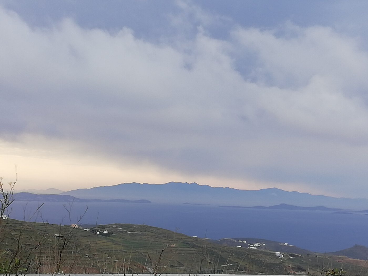 Σύννεφα βροχής πάνω από το πέλαγος, με χωράφια της Τήνου μπροστά