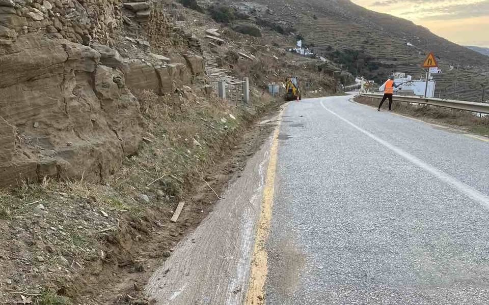 Συνεργείο με εκσκαφέα και εργάτη με πορτοκαλί γιλέκο στον επαρχιακό δρόμο της Καρδιανής Τήνου, με καθαρισμένο το ρείθρο δίπλα στην κίτρινη γραμμή, το απόγευμα της 13ης Οκτωβρίου 2026
