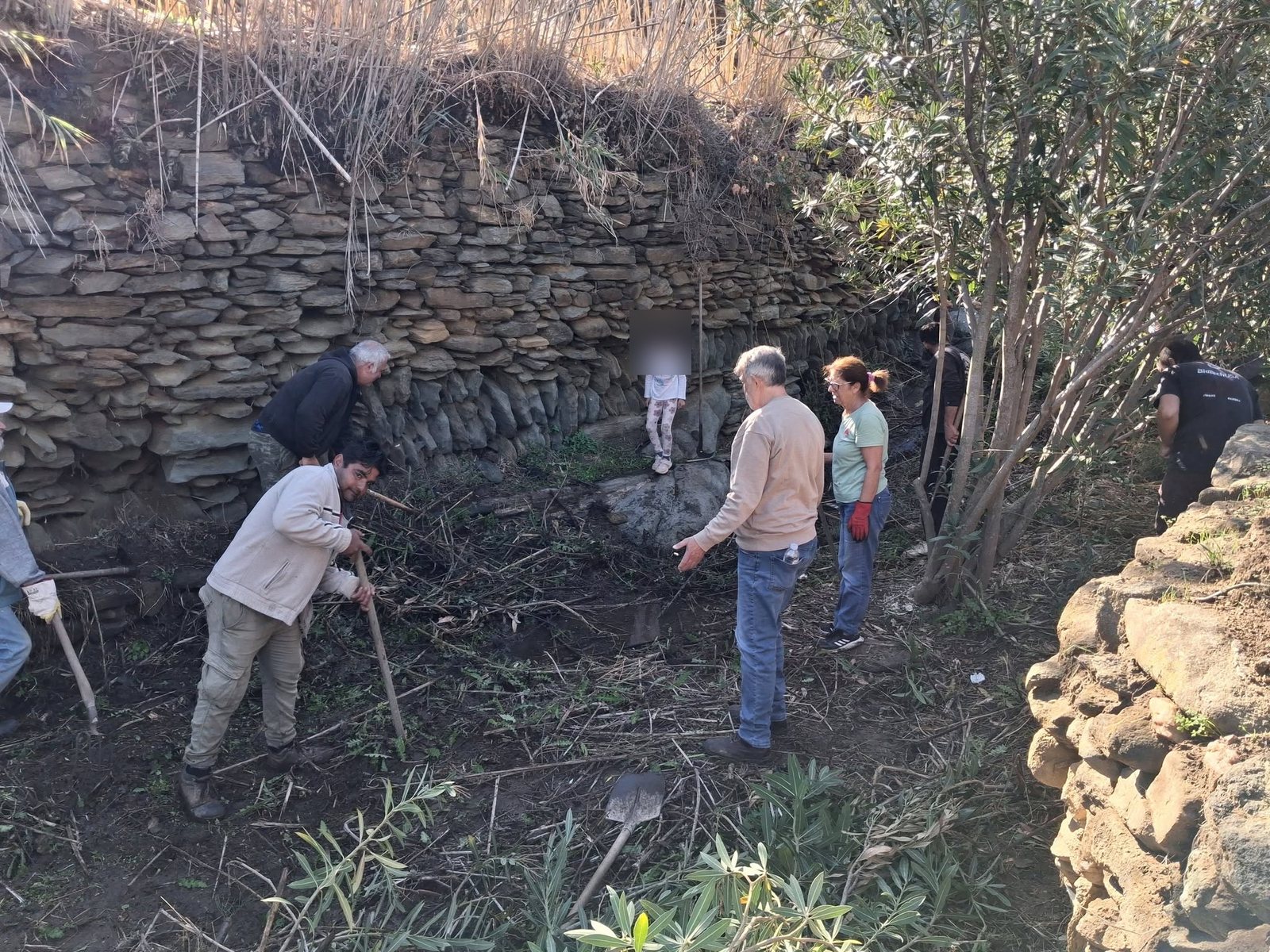 Ομάδα χωριανών στο λαγκάδι της Μεσιανής, μπροστά σε ψηλή ξερολιθιά