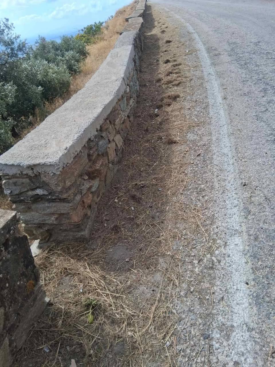 Καθαρισμένη τάφρος απορροής δίπλα σε πέτρινο τοιχίο, στο επαρχιακό οδικό δίκτυο της Τήνου