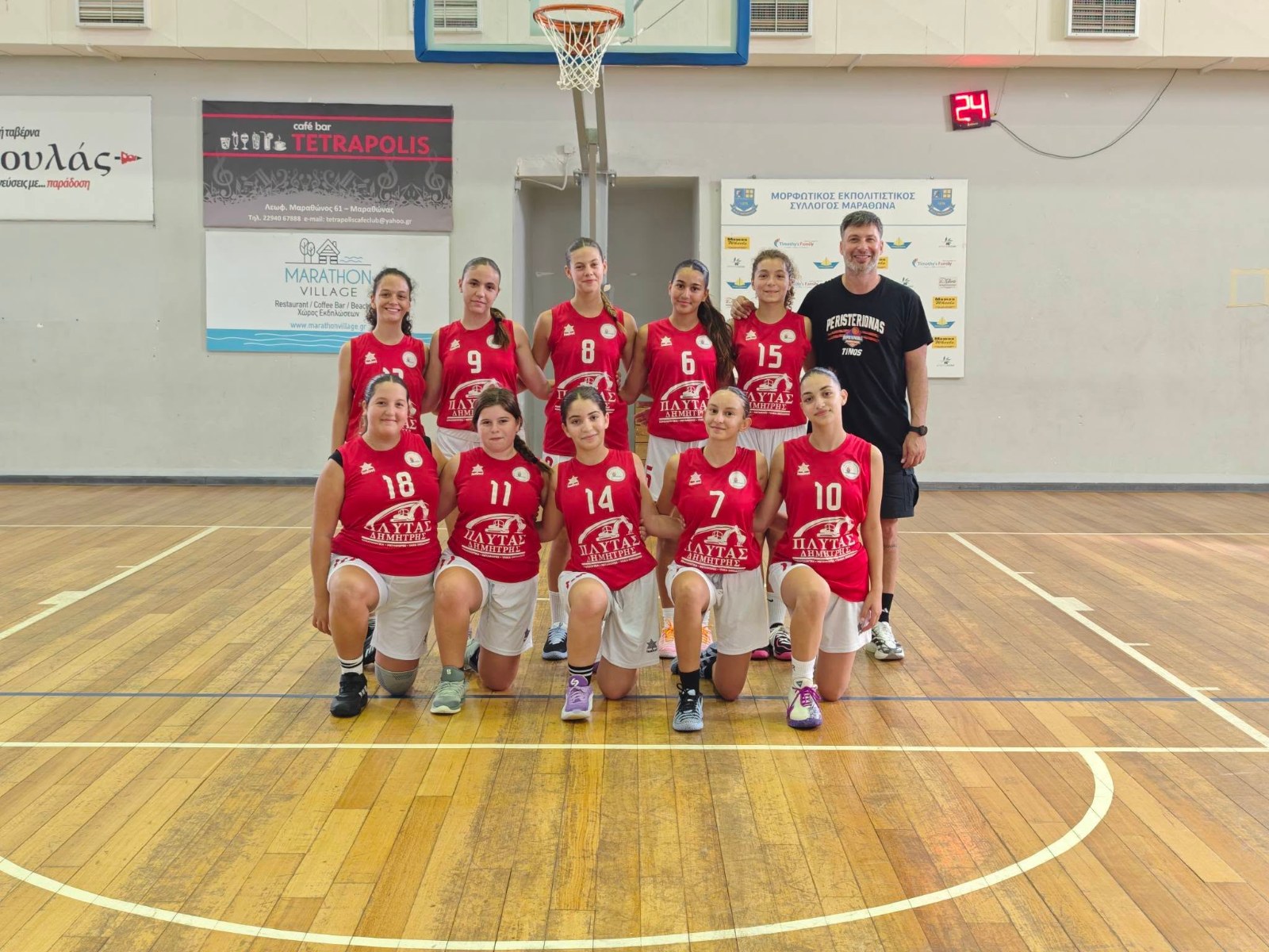 Οι Κορασίδες του Περιστεριώνα Τήνου με κόκκινες φανέλες και τον προπονητή τους στο κλειστό του Μαραθώνα