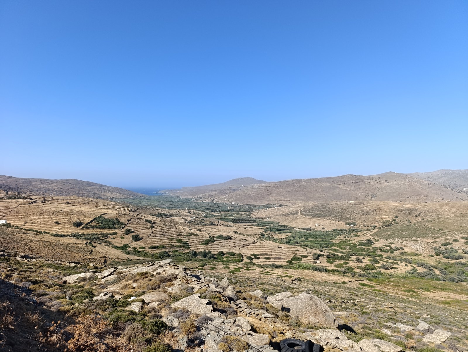 Το Λιβάδι της Κώμης στην Τήνο και στο βάθος η φουρτουνιασμένη Κολυμπήθρα