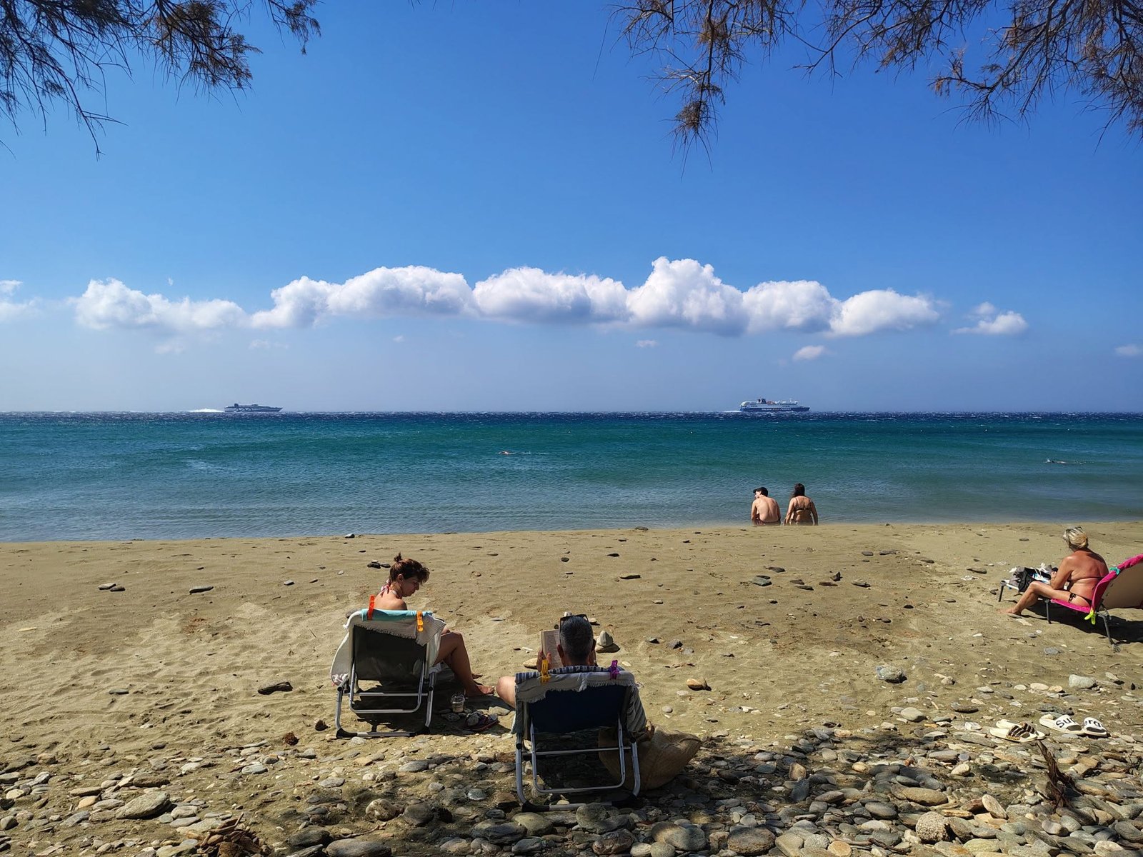 Λουόμενοι σε αμμουδιά της Τήνου με ήρεμη θάλασσα