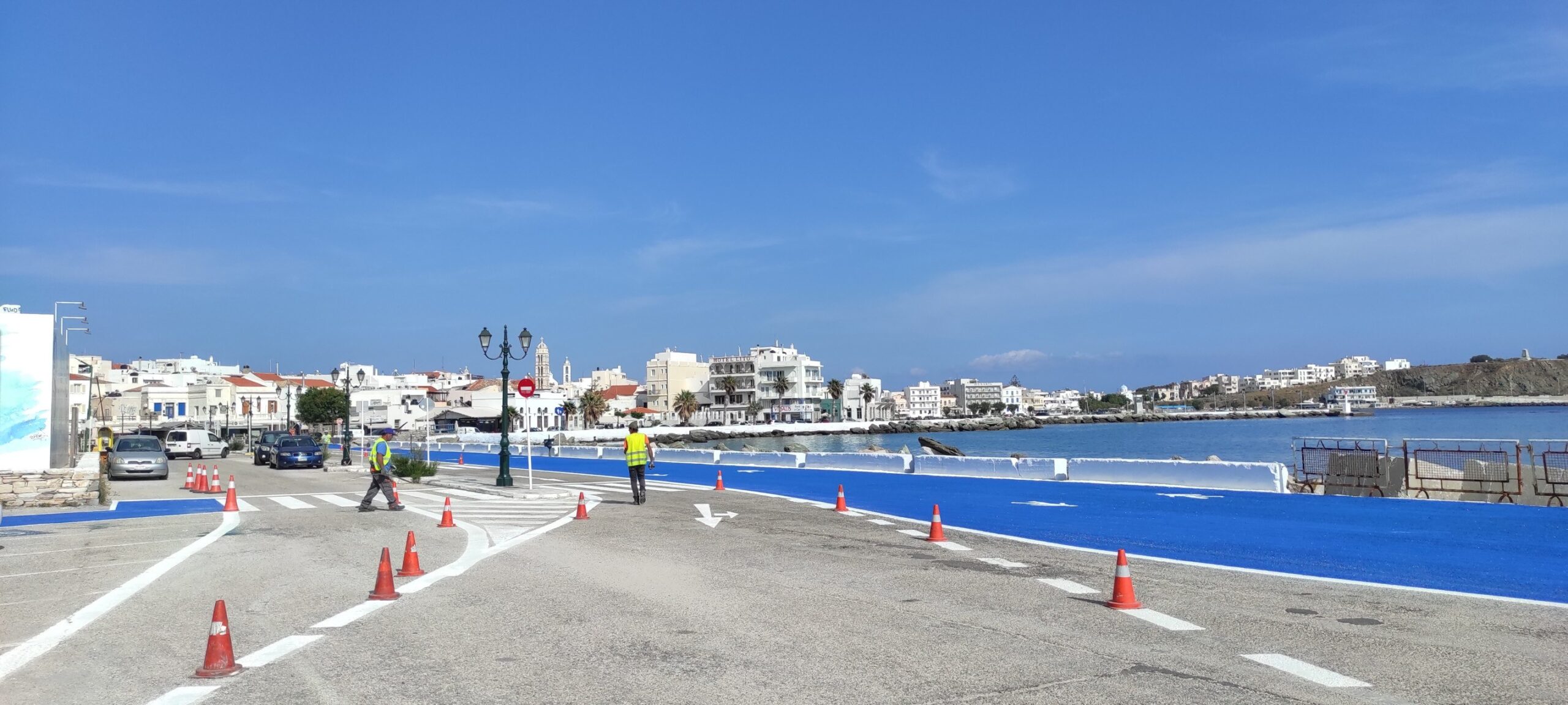 Η παραλιακή οδός της Τήνου με κώνους κυκλοφορίας και θέα στο λιμάνι