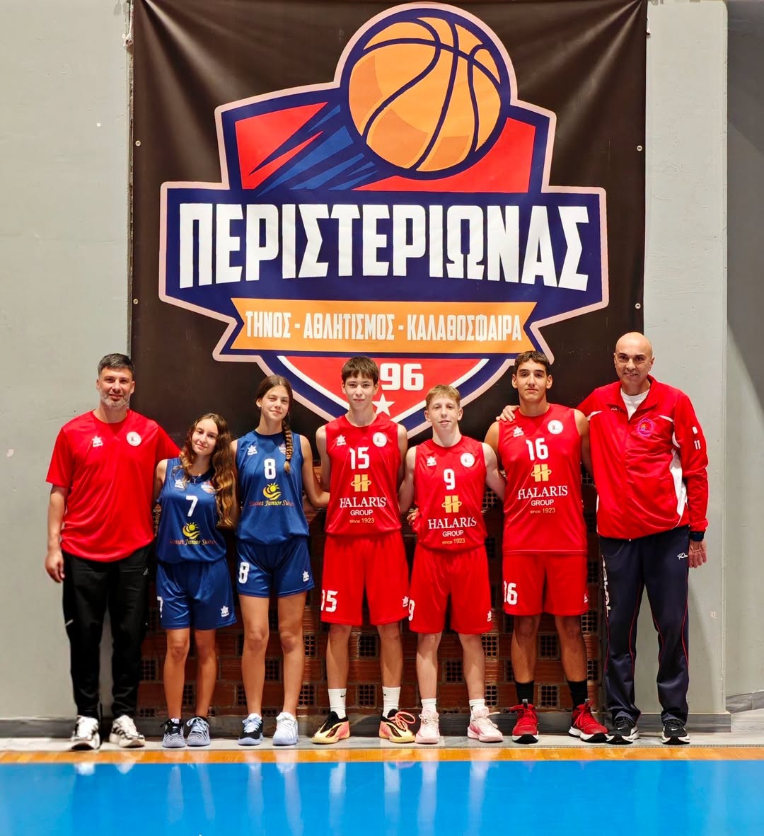 Οι πέντε αθλητές και αθλήτριες του Περιστεριώνα Τήνου που κλήθηκαν στη Μικτή Κυκλάδων, με τους προπονητές τους, μπροστά στο έμβλημα του συλλόγου
