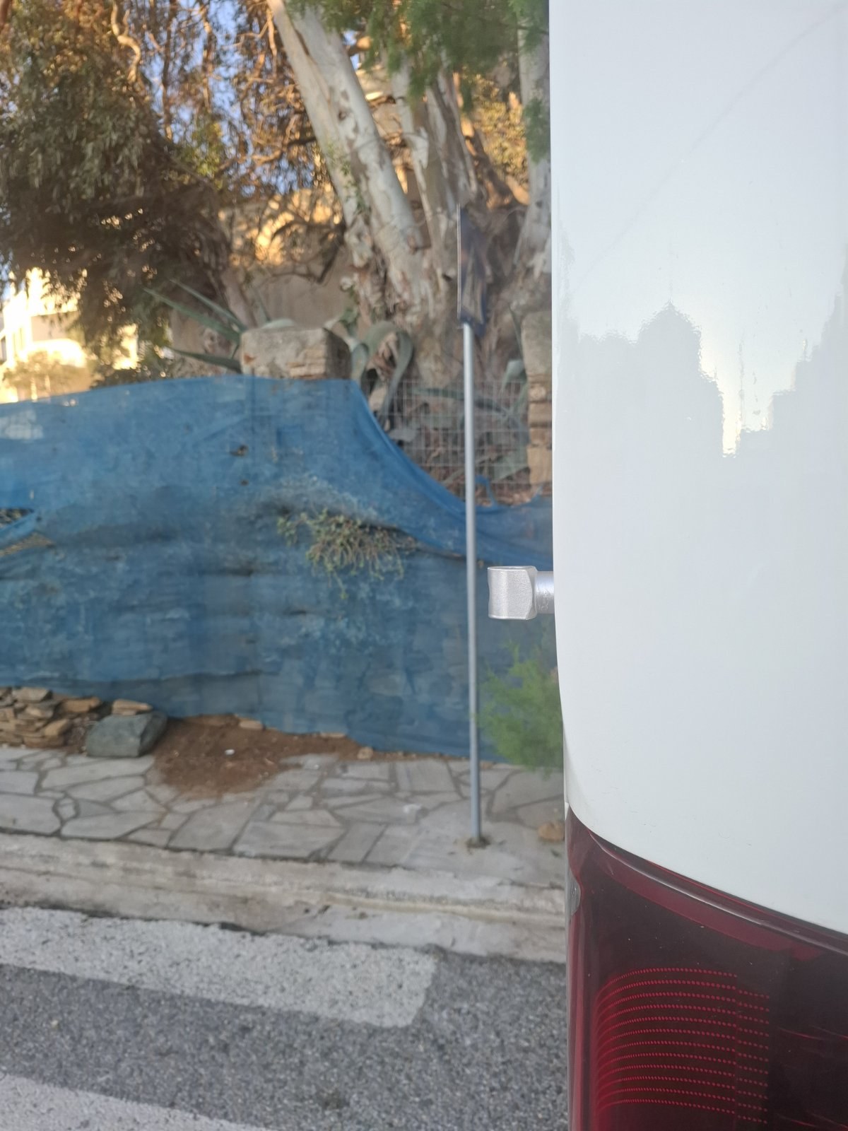 Το πίσω μέρος του πούλμαν δίπλα στον στύλο της πινακίδας της διάβασης, σε απόσταση λίγων εκατοστών