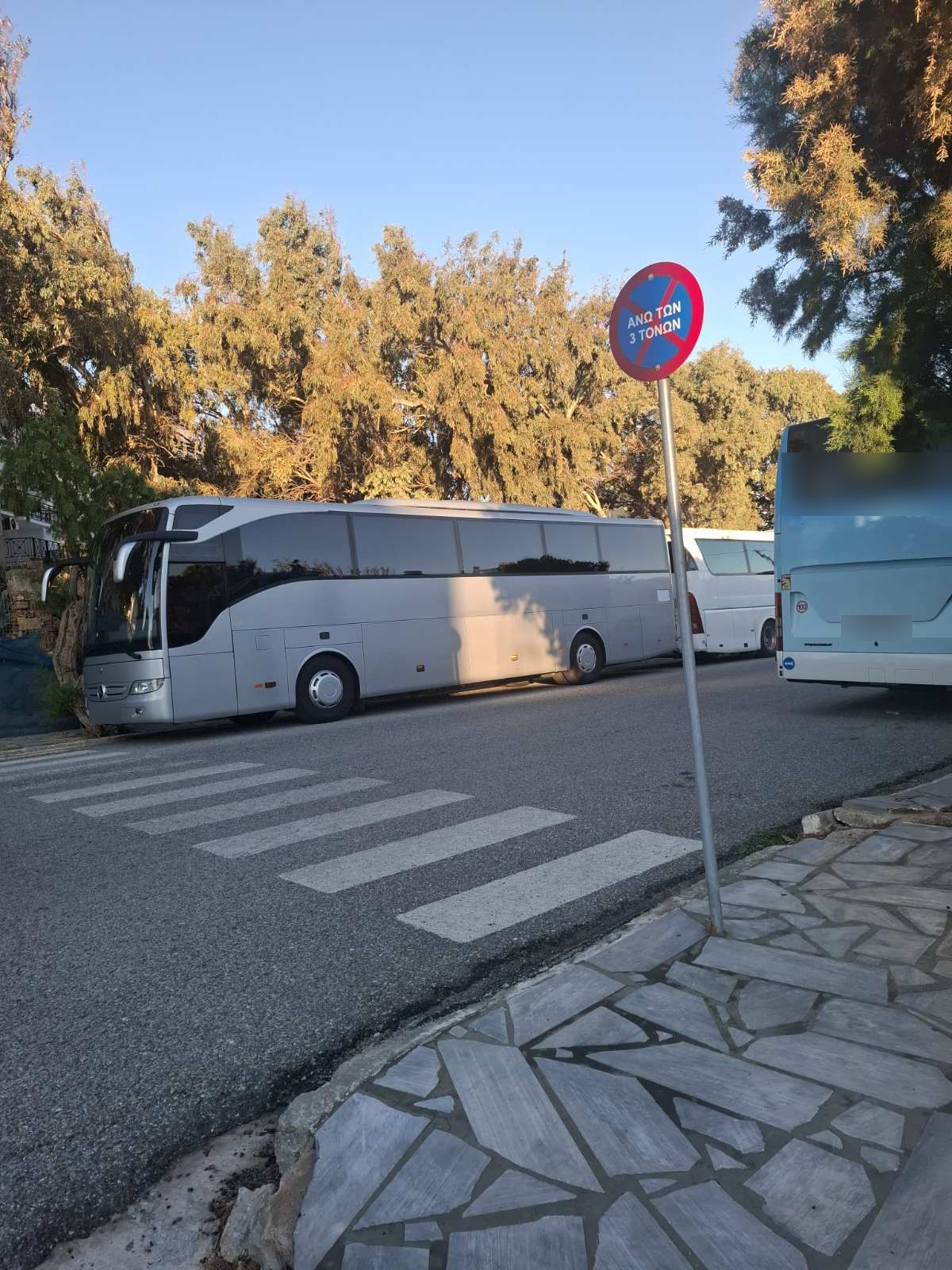Πούλμαν σταθμευμένα δίπλα στη διάβαση, κάτω από πινακίδα που απαγορεύει τη στάση και στάθμευση σε οχήματα άνω των 3 τόνων