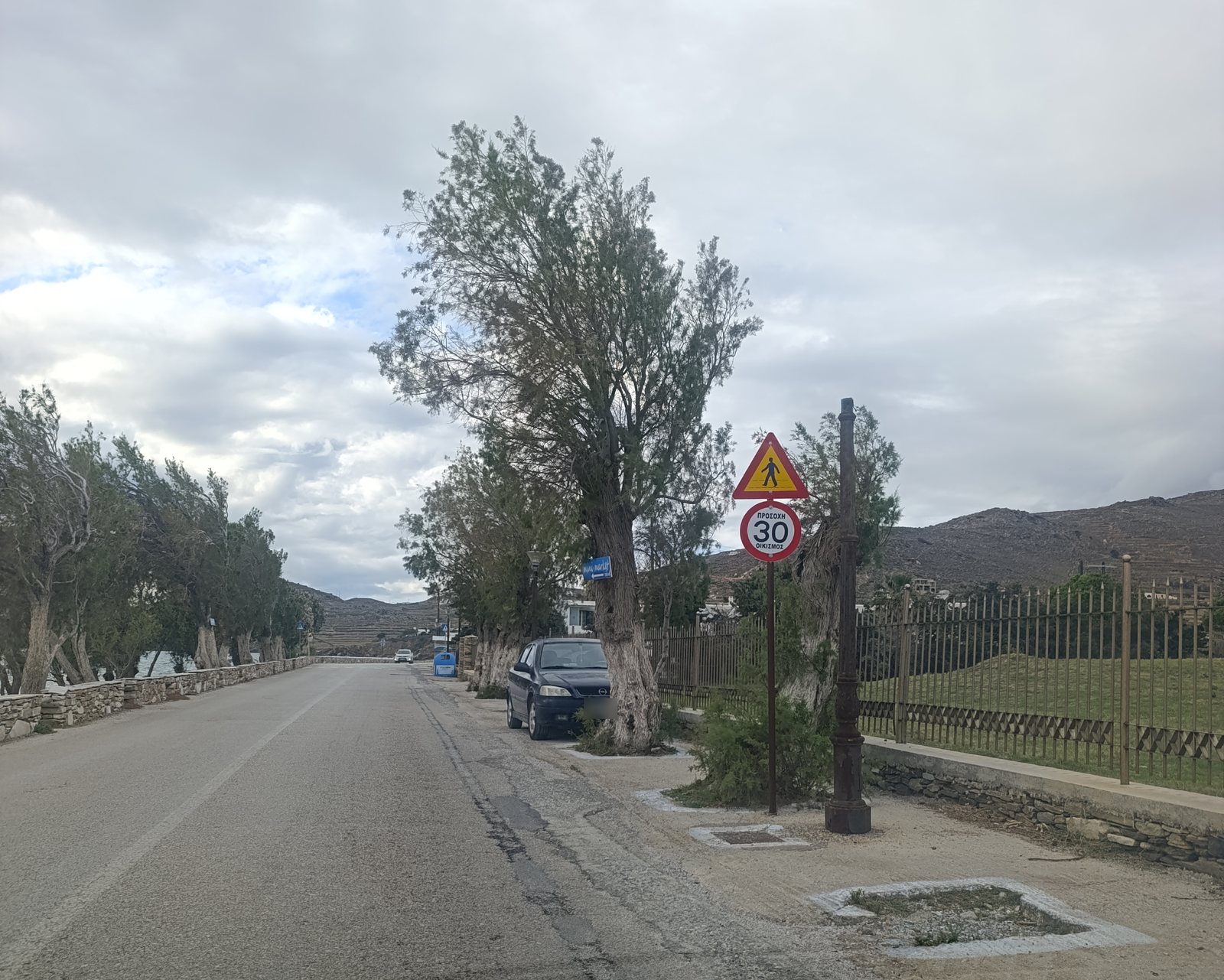 Πινακίδες «Προσοχή πεζοί» και «Προσοχή 30 Οικισμός» στον παραλιακό δρόμο των Κιονίων στην Τήνο