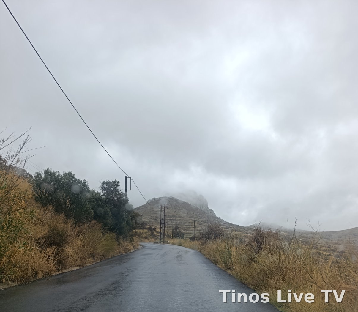 Βρεγμένος δρόμος της Τήνου προς το Εξώμβουργο, με την κορυφή μέσα στα σύννεφα