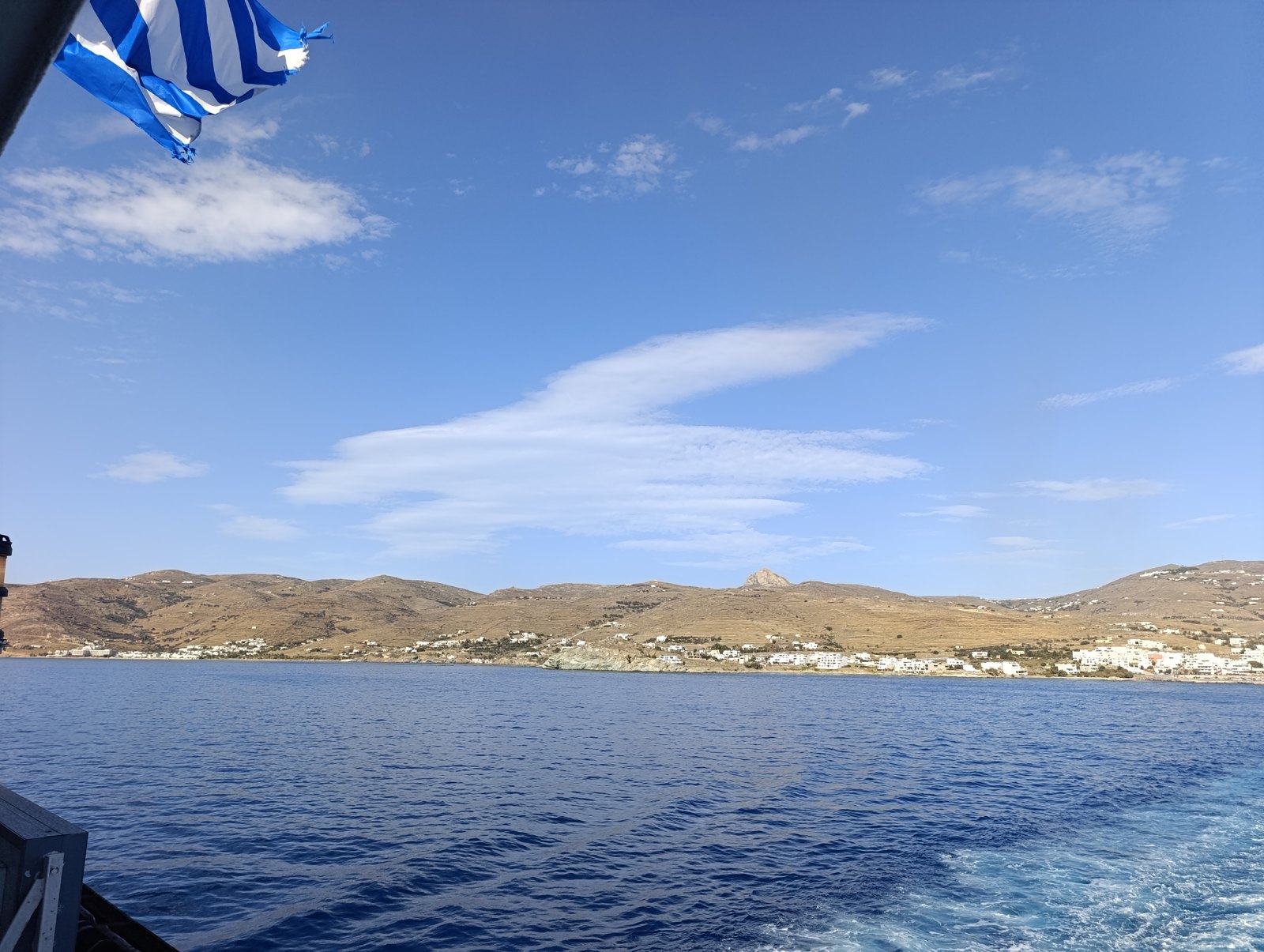 Η Τήνος και το Εξώμβουργο από τη θάλασσα, με ελληνική σημαία και γαλάζιο ουρανό