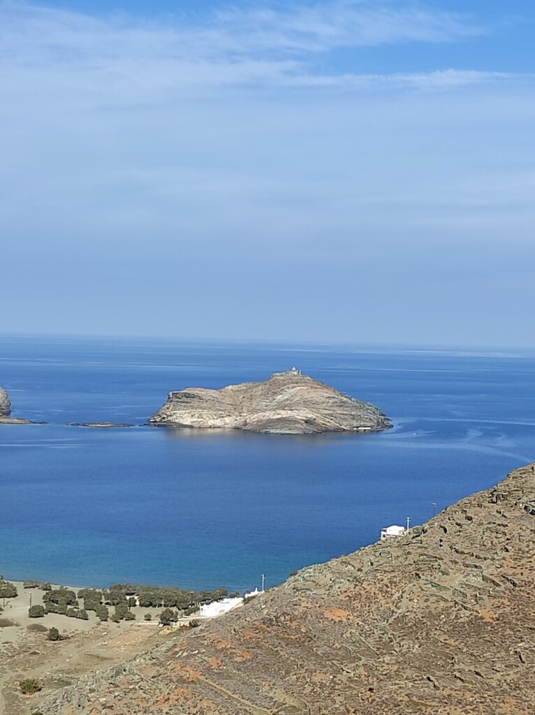 Γαλάζια θάλασσα στον Πάνορμο της Τήνου με το νησάκι Πλανήτης