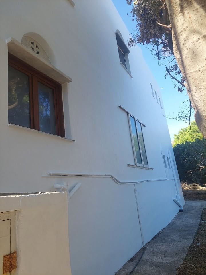Φρεσκοασβεστωμένος τοίχος με παράθυρα στους ξενώνες της Παναγίας της Βουρνιώτισσας